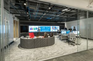 view into a social media center with large video wall, couch, and workers collaborating