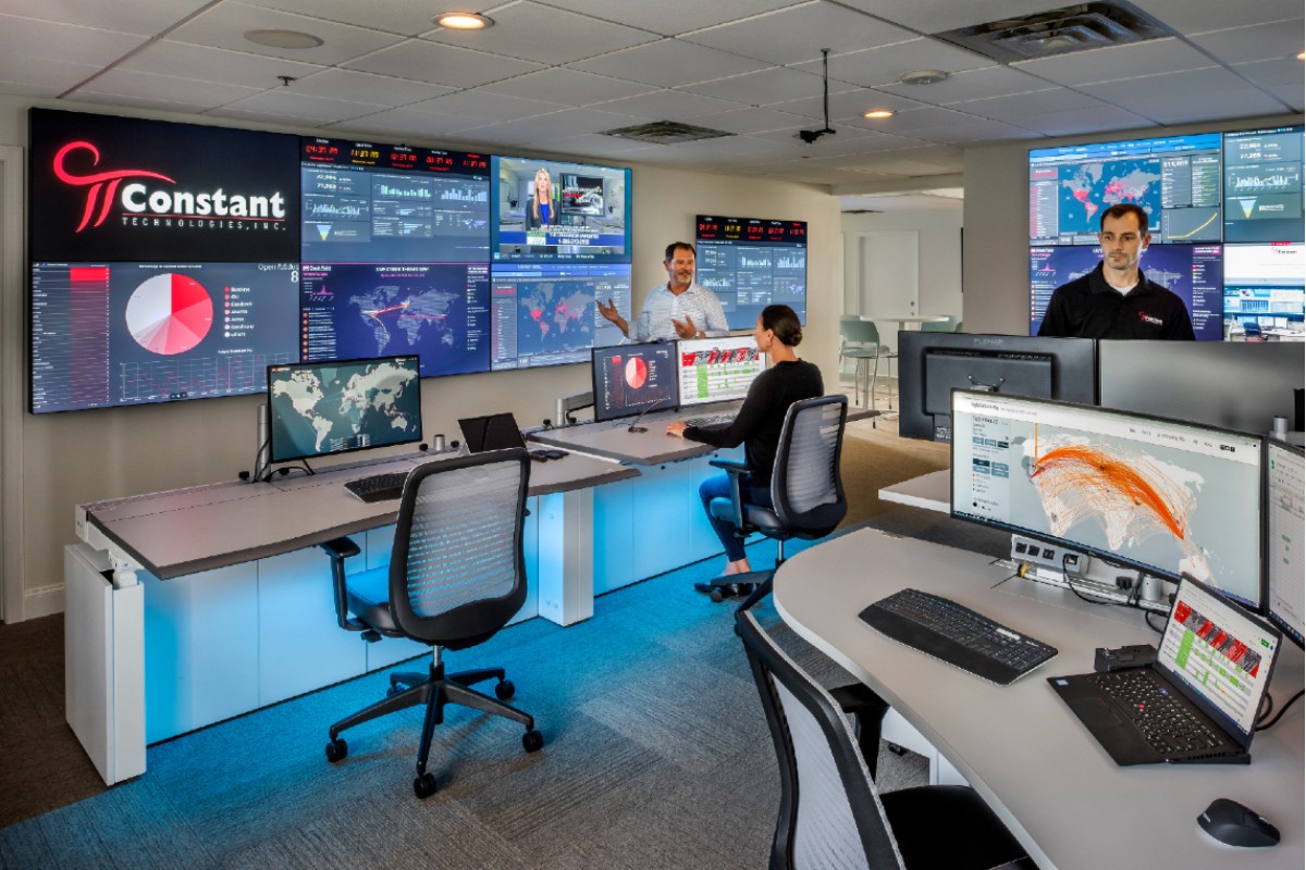 Three people working in Constant Technologies Operations Center with video walls and consoles