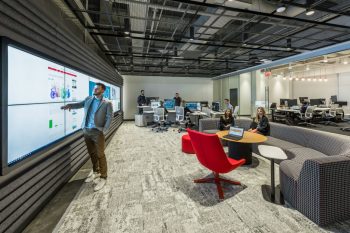 Modern collaboration space with large display, casual seating, and open workspace for coordination