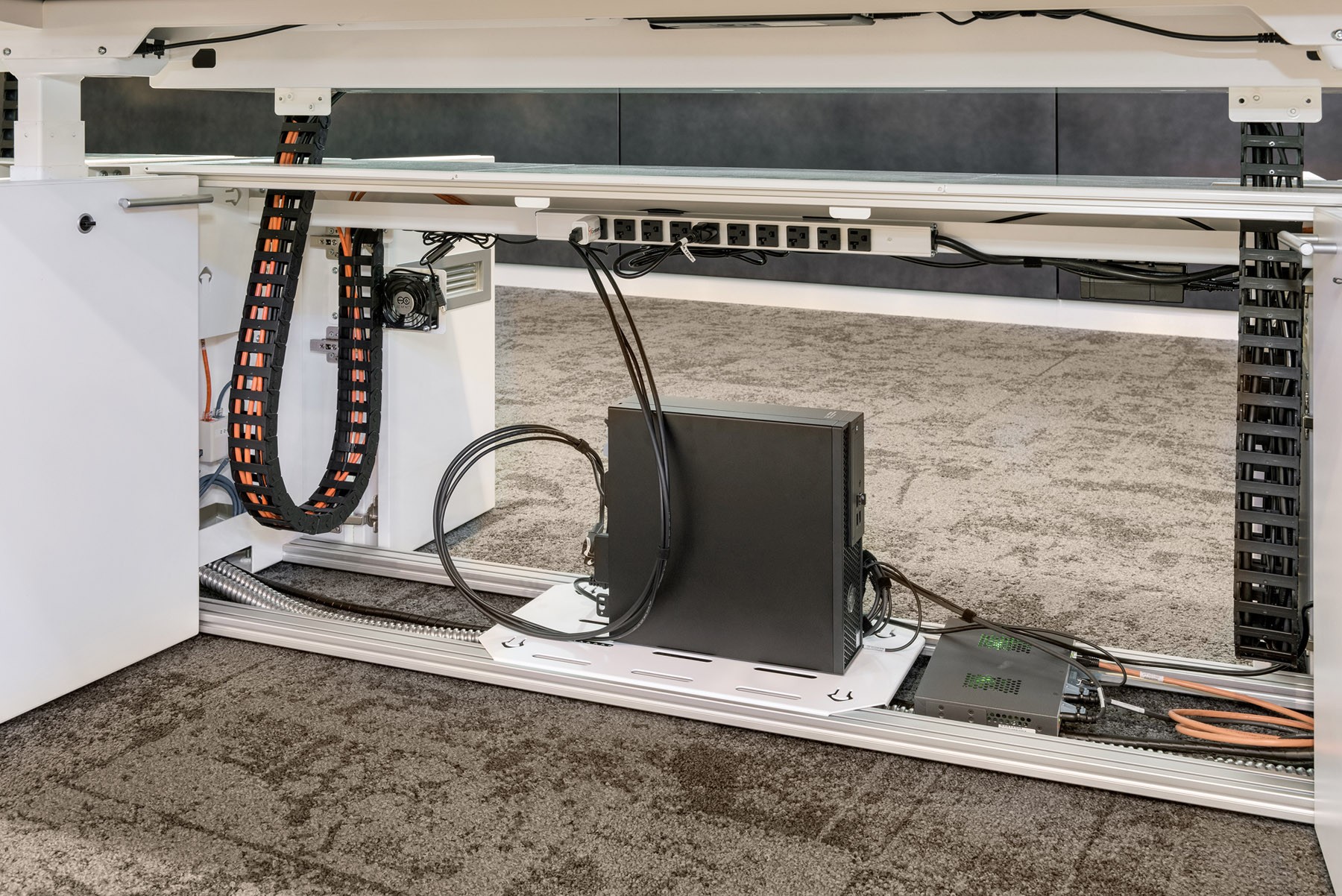 a computer sitting underneath a desk with cables coming out of it