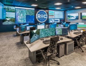 Realtime operations center with large central video wall and rows of consoles
