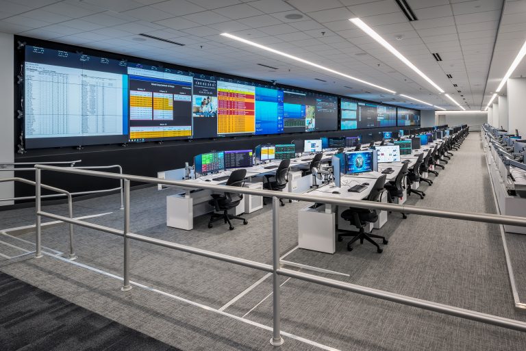 a large room with lots of computers and large screens with graphics and data on them