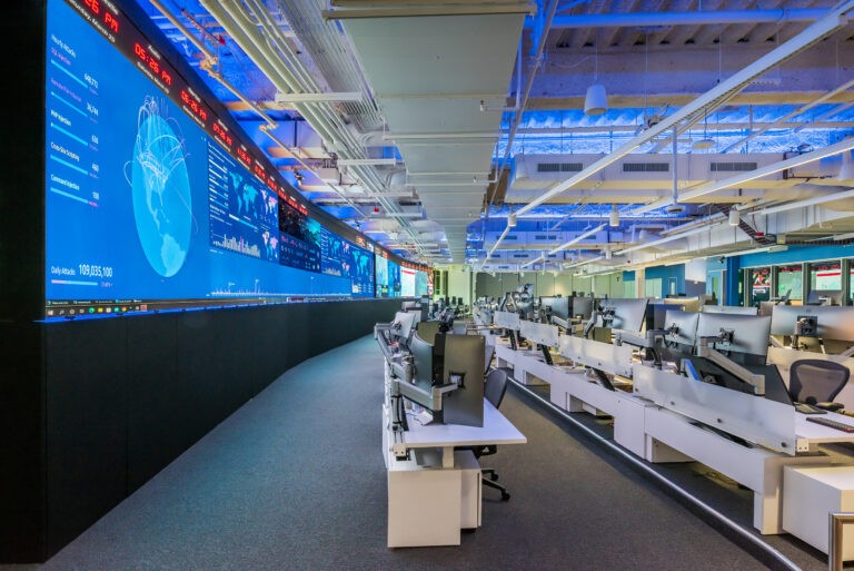 a large screen in a large room shows the earth and some numbers