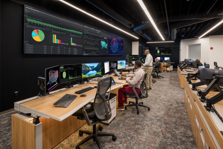 a group of people are sitting at desks in front of a large screens with graphics and charts on it